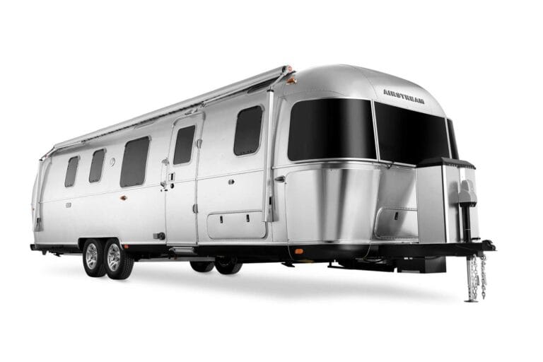 Modern travel trailer parked in a scenic camping site under a sunset sky
